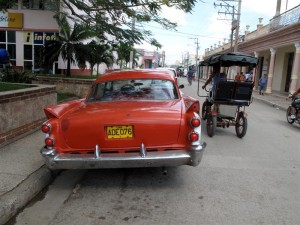 old-car-medium Chevvies, Oldsmobiles and Studebakers share the road with horse buggies and bullock carts.